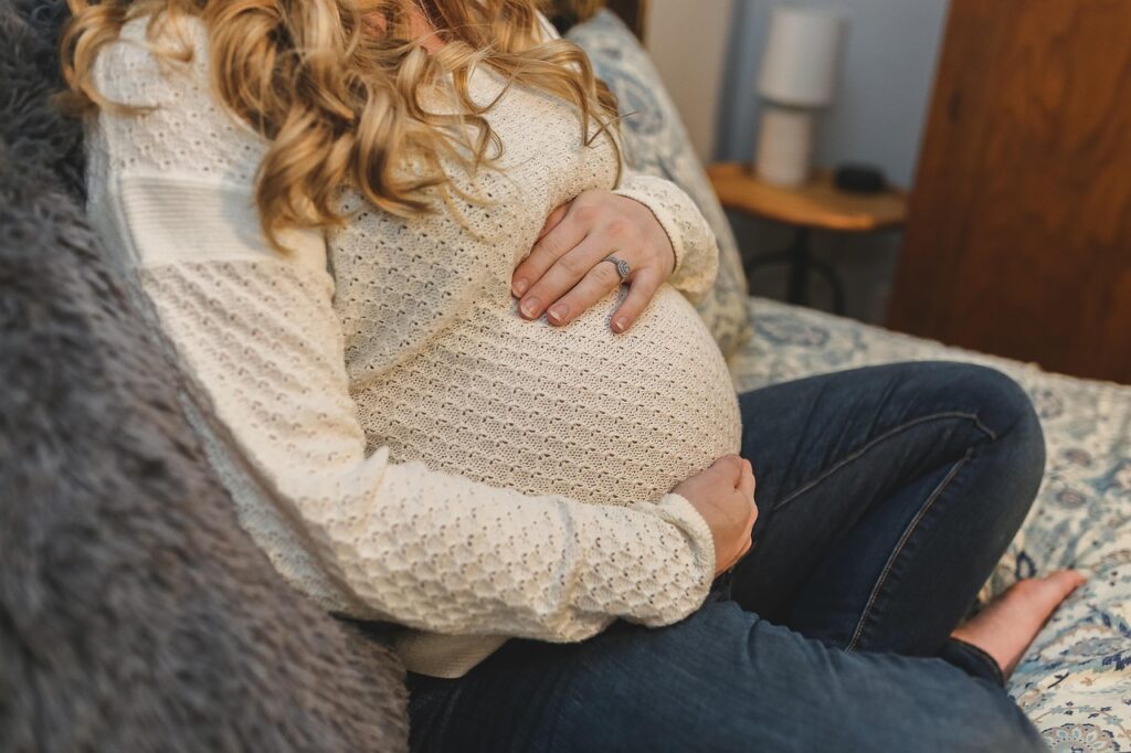 Pregnant woman with type 1 diabetes smiling and holding her bump in soft natural light, with calm, affirming energy.
